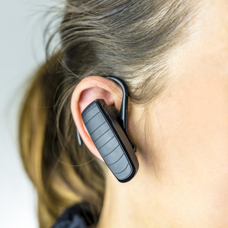 Naheaufnahme von einem Bluetooth Headset mit Bügel direkt am Ohr